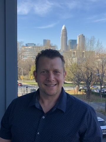 Karl Hoffmann, owner of Heritage, with the Charlotte skyline behind him